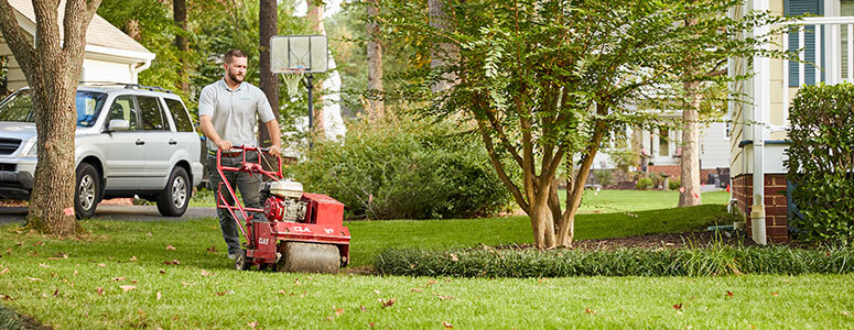 worker aerating lawn
