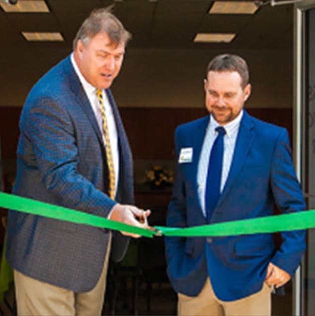Virginia Green leaders cutting a green ribbon at the opening of a new branch